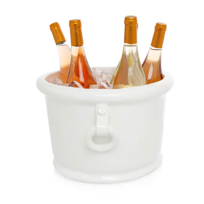 White ceramic oval ice bucket with ring handles, holding four bottles of wine and ice.