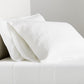White Washed Linen Sheet Set with two pillowcases and a flat sheet on a bed.