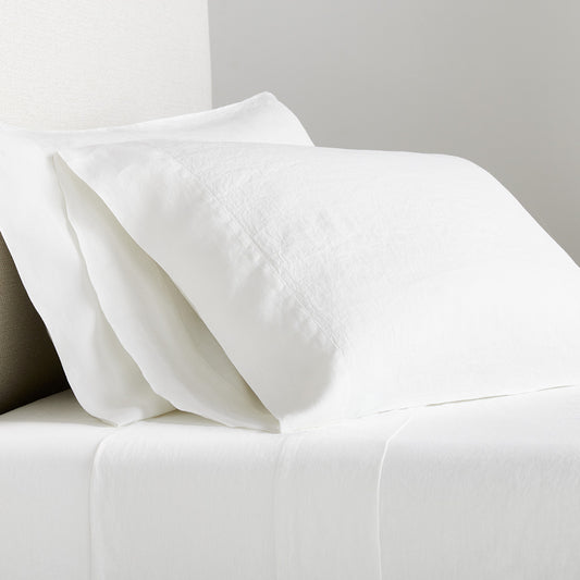 White Washed Linen Sheet Set with two pillowcases and a flat sheet on a bed.