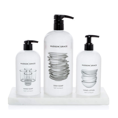 White marble triple soap and lotion tray holding three white Hudson Grace bottles.