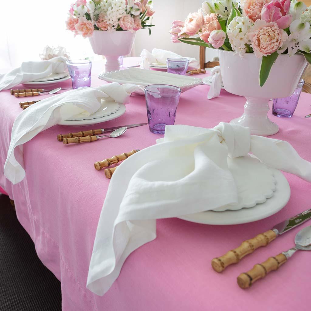 White HG Signature hand-dyed 22" linen napkins with mitered corners, styled on a pink tablecloth.